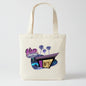 An off-white canvas tote bag featuring a colorful graphic print of a retro 'Glow Motel' with purple palm trees and a stylized building.