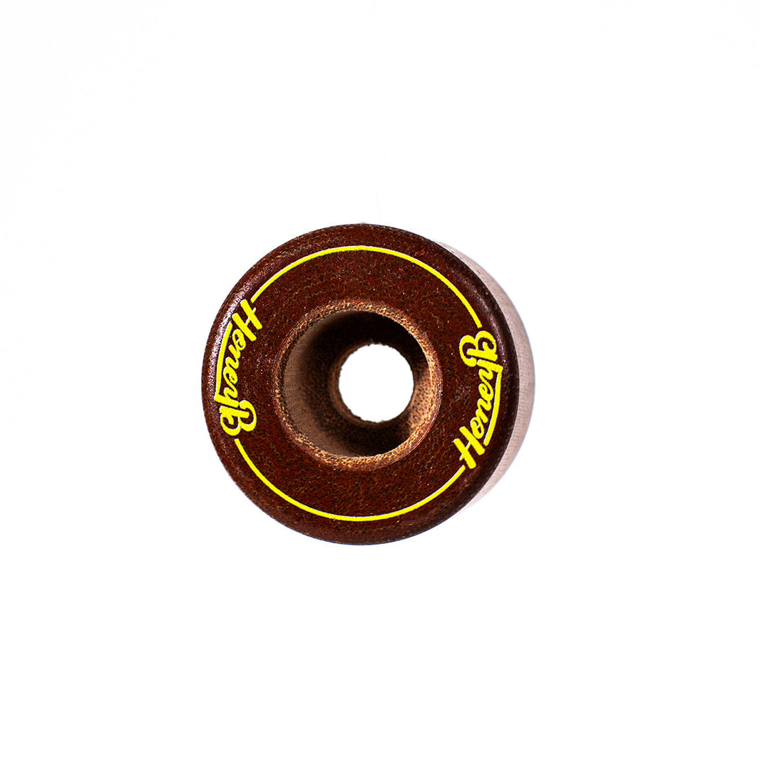 A single skateboard wheel with a dark brown metallic finish, featuring a yellow circular border and the brand name 'Honest' printed in yellow script on both sides.
