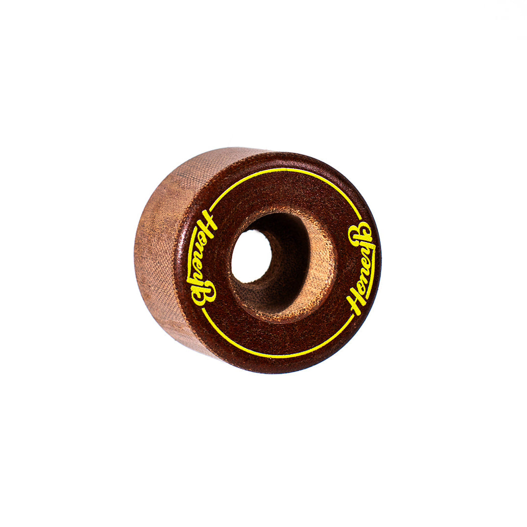 A single wooden skateboard wheel with a medium brown wood grain finish, featuring a bright yellow ring and the brand name 'Heavy' printed in yellow script on both sides.