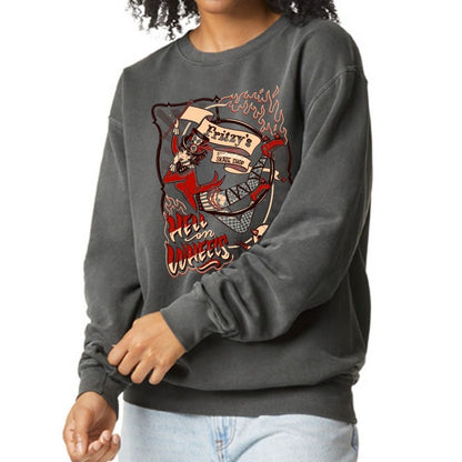 A person wearing a dark charcoal gray sweatshirt with a large graphic print on the front. The graphic features a tattoo-style illustration with red, beige, and black details and the text 'Fritzy's Skate Shop' and 'Hell on Wheels'.