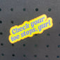 A die-cut sticker with the phrase 'Check your toe stops, gurl' in purple text outlined in yellow, placed on a dark perforated foam background.