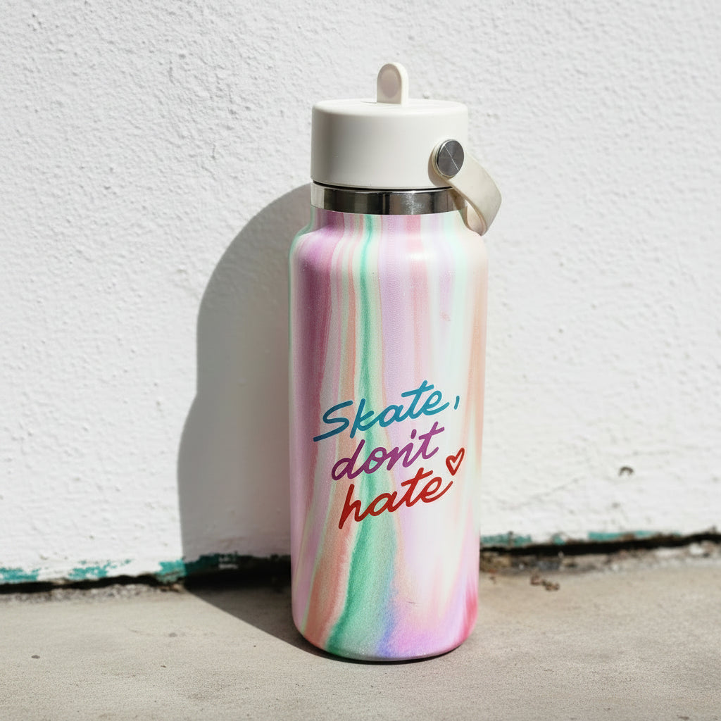 A pastel marbled water bottle with a white lid and carrying loop, featuring the text 'Skate, don't hate' in blue, pink, and red script, set against a white wall.