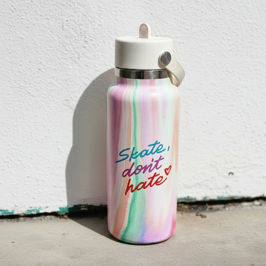 A pastel marbled water bottle with a white lid and carrying loop, featuring the text 'Skate, don't hate' in blue, pink, and red script, set against a white wall.