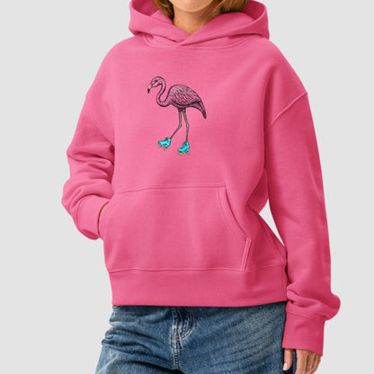 A person wearing a bright pink pullover hoodie with a central flamingo graphic in pink and teal, paired with blue jeans, against a light gray studio background.