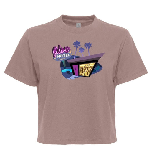 A short-sleeve crewneck t-shirt in a dusty mauve or taupe color, featuring a retro 1960s-style graphic of the 'Glow Motel' with purple palm trees and a neon sign on the chest.